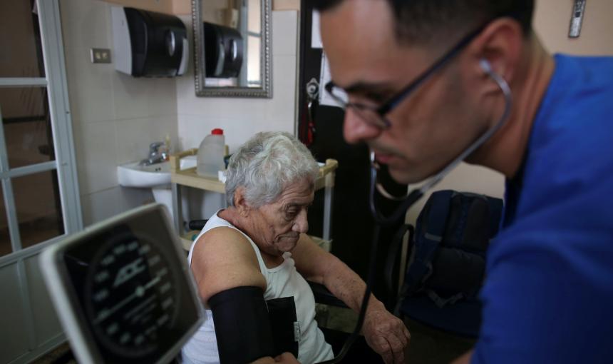 A nurse takes the blood pressure of a patient during a home check-up.
