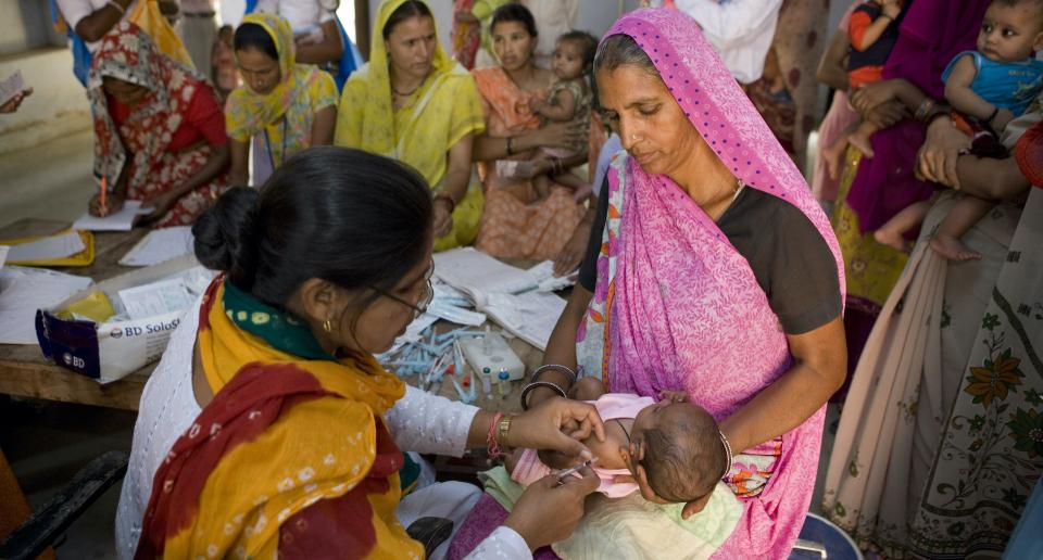 Two women administering medical care to a baby
