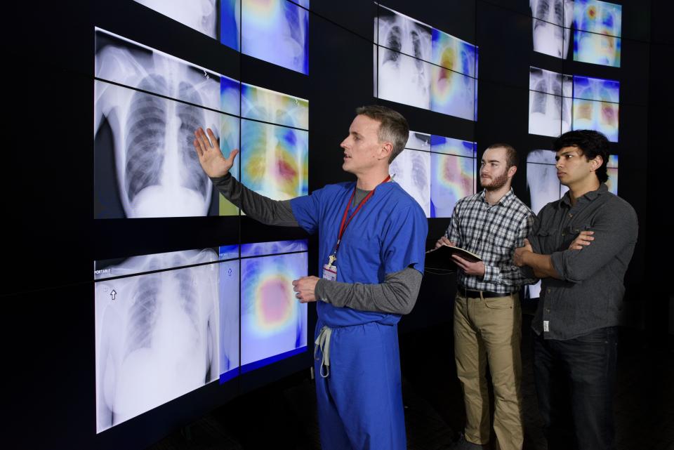 Radiologist Matthew Lungren, left, meets with graduate students Jeremy Irvin and Pranav Rajpurkar to discuss the results of detections made by the algorithm.