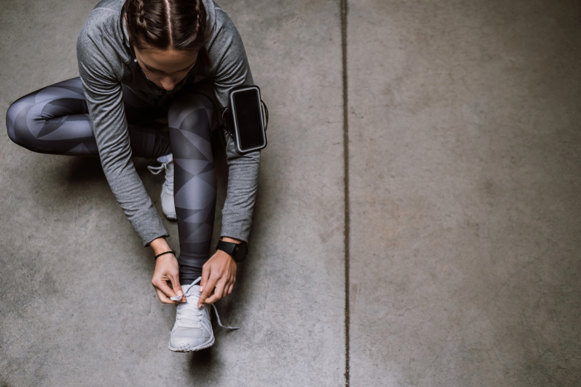 A runner with a smartphone laces her shoes