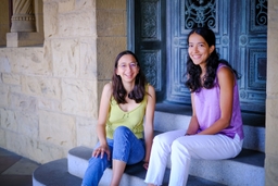 Two smiling HAI Fellows sitting on steps