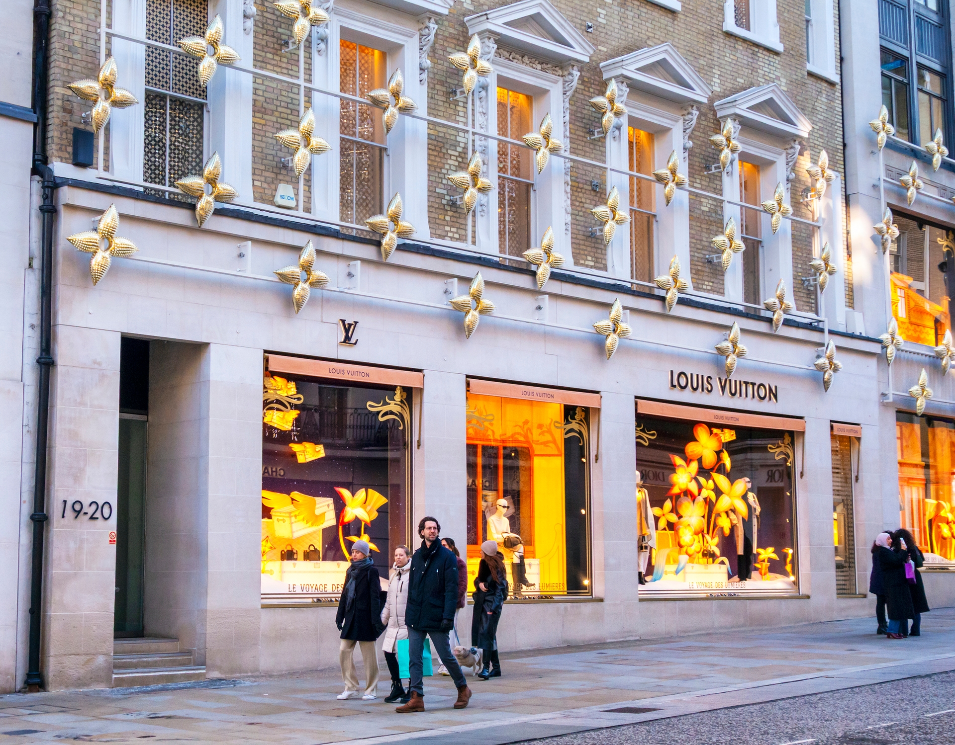 Pedestrians walk by a Louis Vuitton store