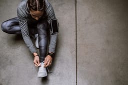 A runner with a smartphone laces her shoes