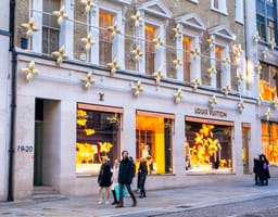 Pedestrians walk by a Louis Vuitton store