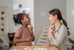 A child works with a speech pathologist to sound out words