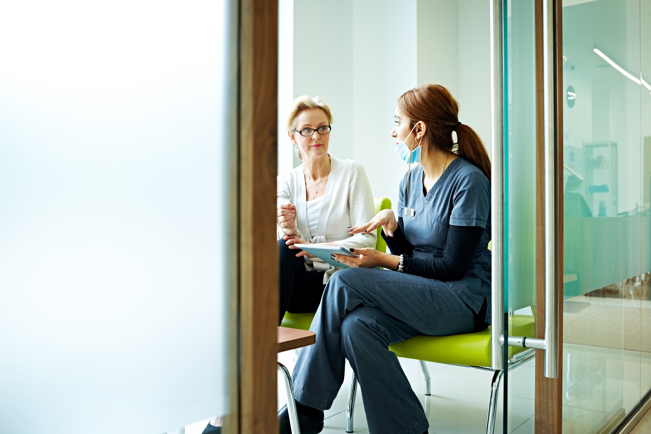a doctor talks to her patient while referring to a tablet