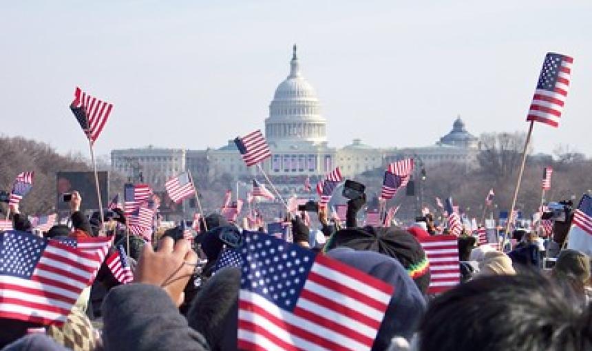 Attendees at a U.S. presidential inauguration wave flags with the Capitol Building in the background.