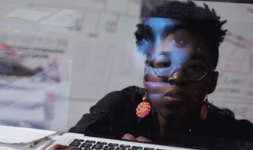 Image of Joy Buolamwini reflected in her computer screen. 