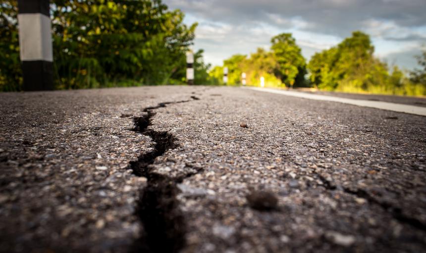 A deep crack in a paved road caused by an earthquake