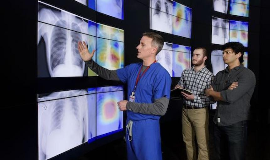 Radiologist Matthew Lungren, left, meets with graduate students Jeremy Irvin and Pranav Rajpurkar to discuss the results of detections made by the algorithm.