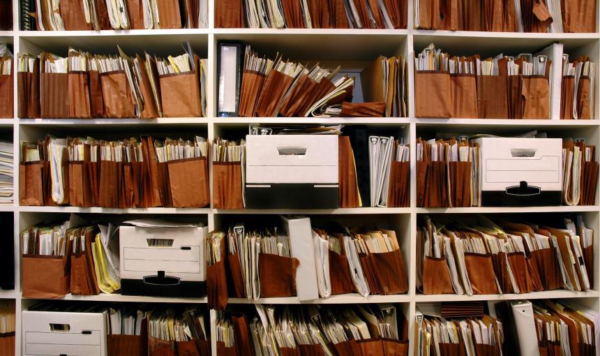 In this photo, stacks and stacks of paper files sit on a large shelf.