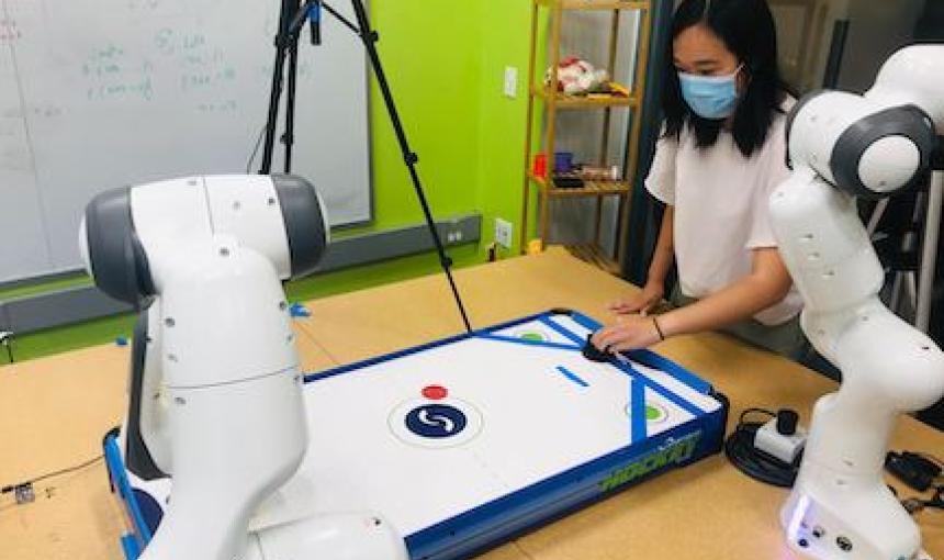 A doctoral student plays air hockey with a robotic arm.