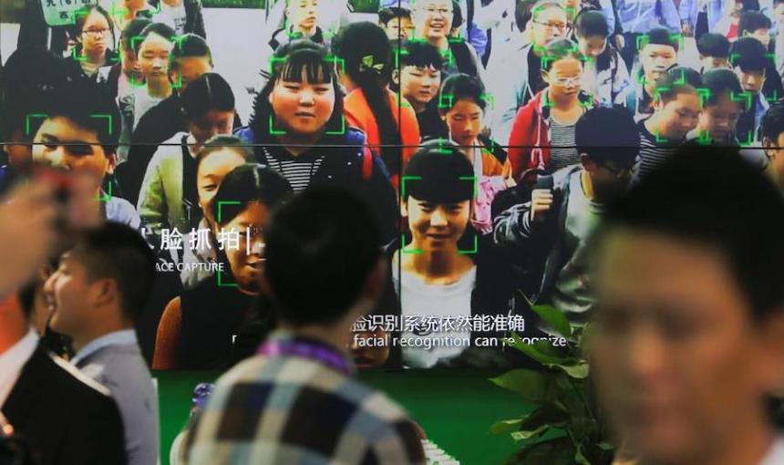 People walk by a screen showing facial recognition technology at an exhibition in Beijing. 