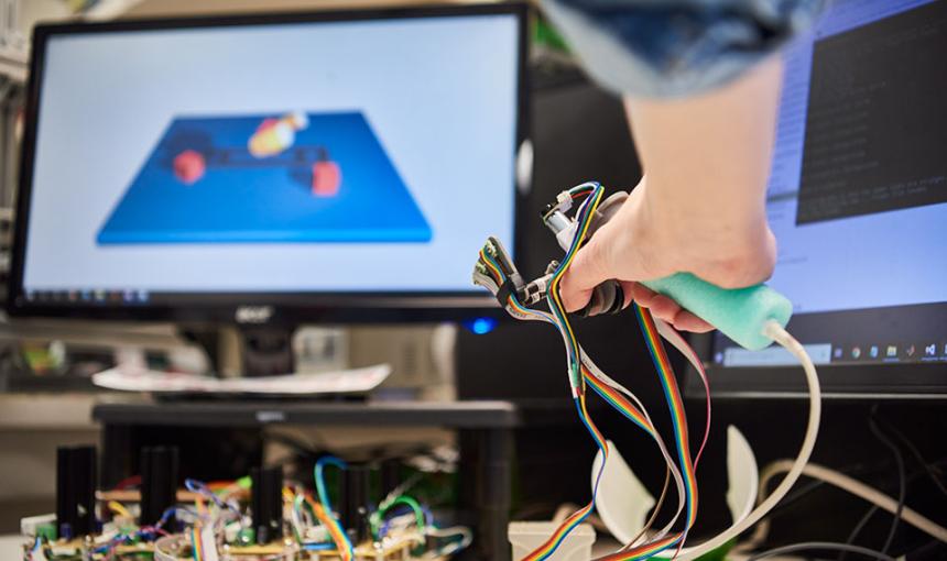 A human's hand is navigating a screen with a robotic controller