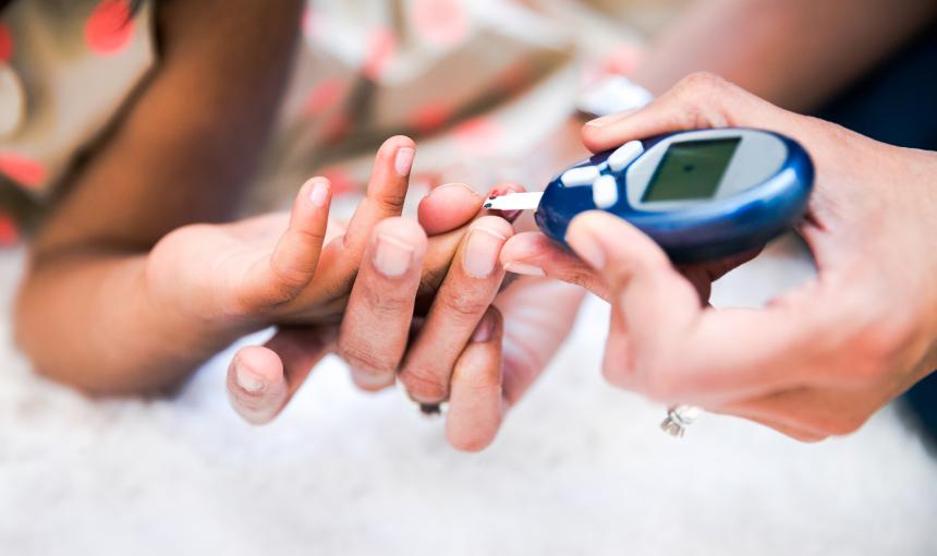 Photo of a mother checking her daughter's diabetes by monitoring blood glucose.