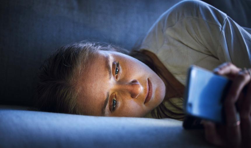 Woman lying on couch staring at her phone