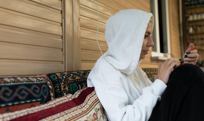 A woman in a white hoodie sweatshirt stares on her smartphone.