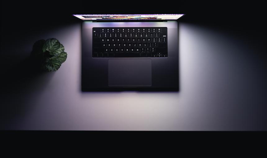 Top view of a laptop on a table, glowing screen in the dark.