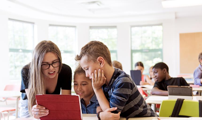 School children and a teacher in class using a digital tablet