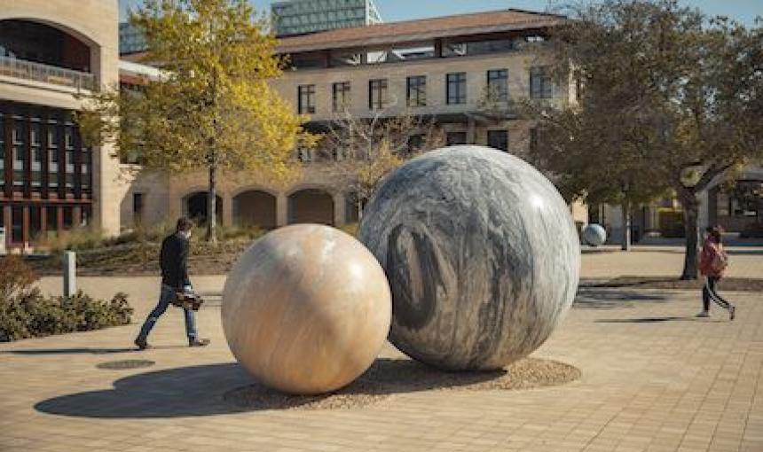 Students walk by an art sculpture on Stanford campus.