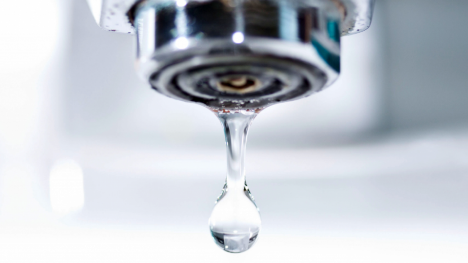 A close up image of a faucet with a single drip of water