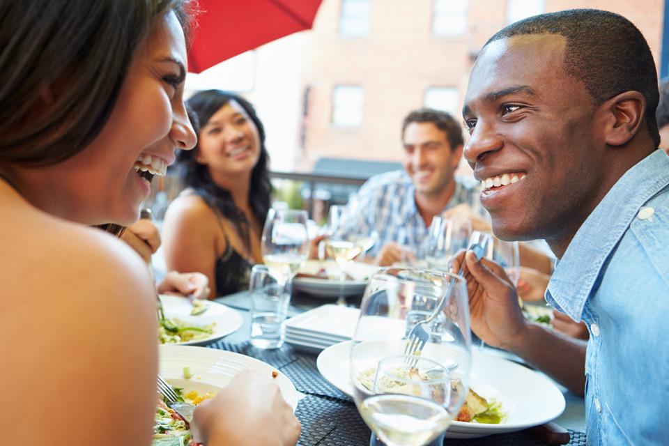 A group of friends eat dinner at an outdoor restaurant. 
