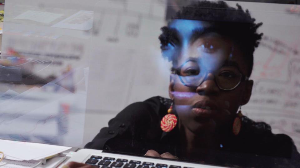 Joy Buolamwini's face reflected in her computer screen.