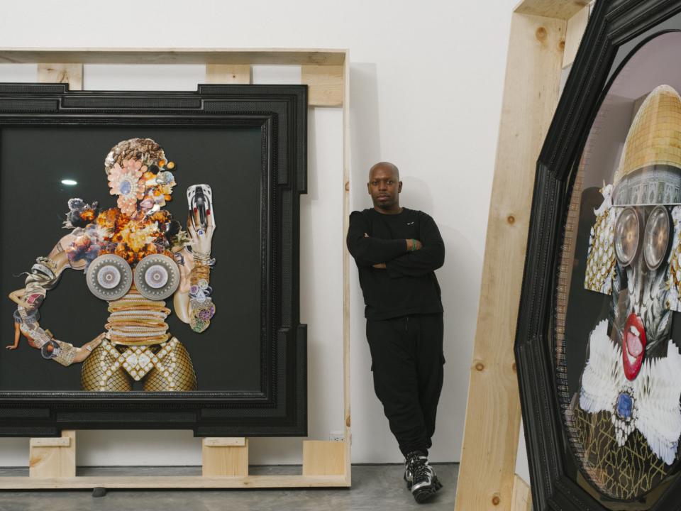Artist Rashaad Newsome leans against a wall surrounded by his collage and sculpture work. 