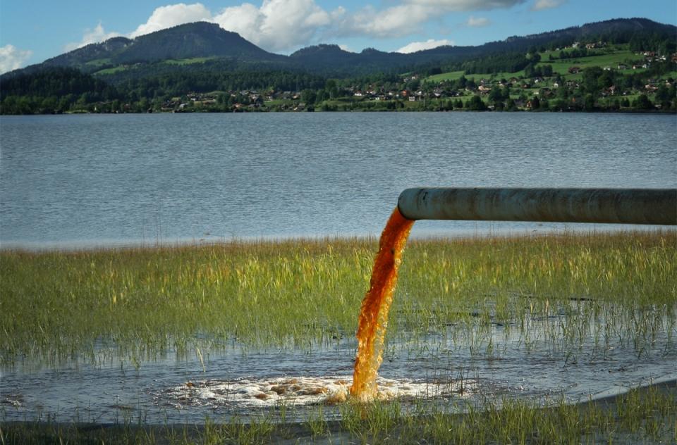 Image of a pipe spilling dirty water into a clean lake