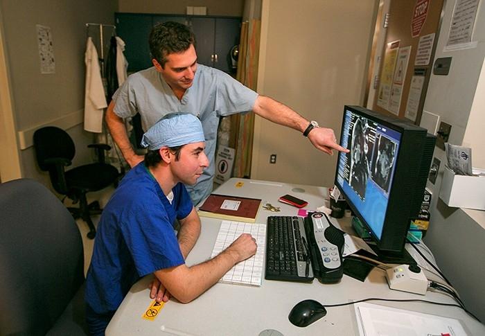 Two doctors consult a computer screen at the Stanford Advanced Cardiovascular Therapeutics and Surgical Biomechanics Translational Research Laboratory.