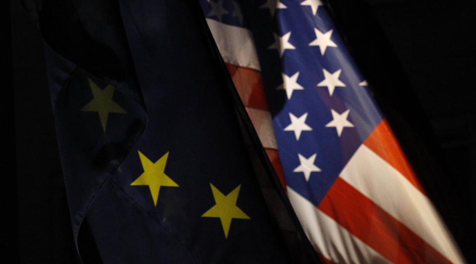 A photograph depicts the EU and US flags.