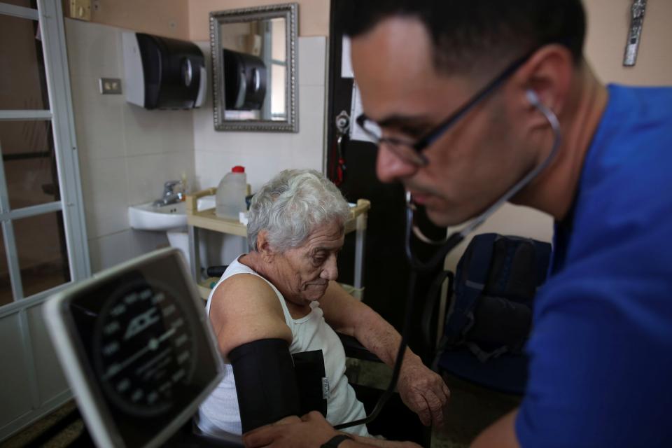 A nurse takes a woman blood pressure during an in-home check-up. 