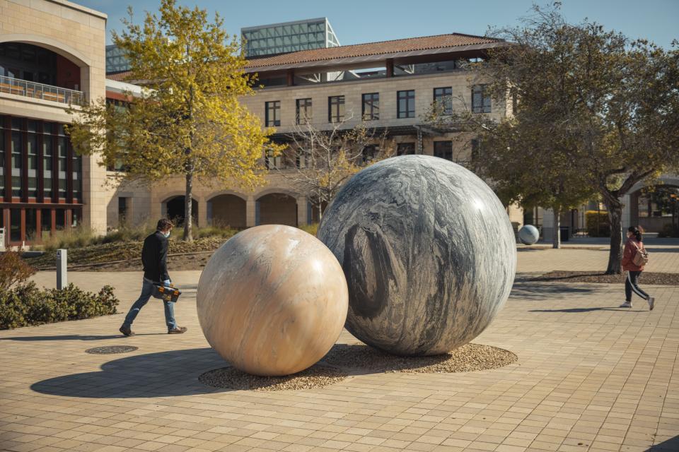 Students walk by an art sculpture on Stanford campus.