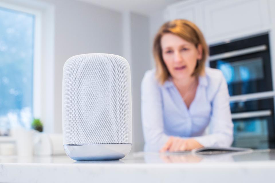 Woman In Kitchen Asking Digital Assistant Question