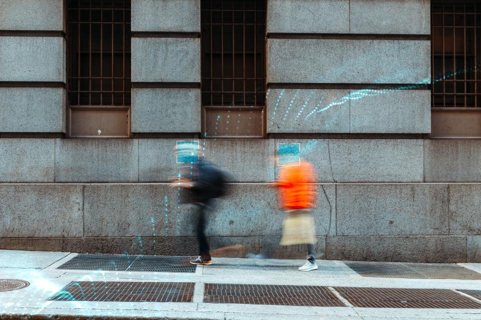 People with blurred faces walking by on a street