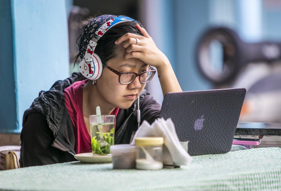 A young student watches video on her computer at a cafe