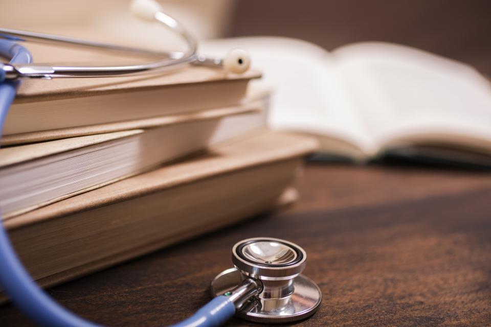 a tables with 3 books stacked on top of each other and a stethoscope laid across the books