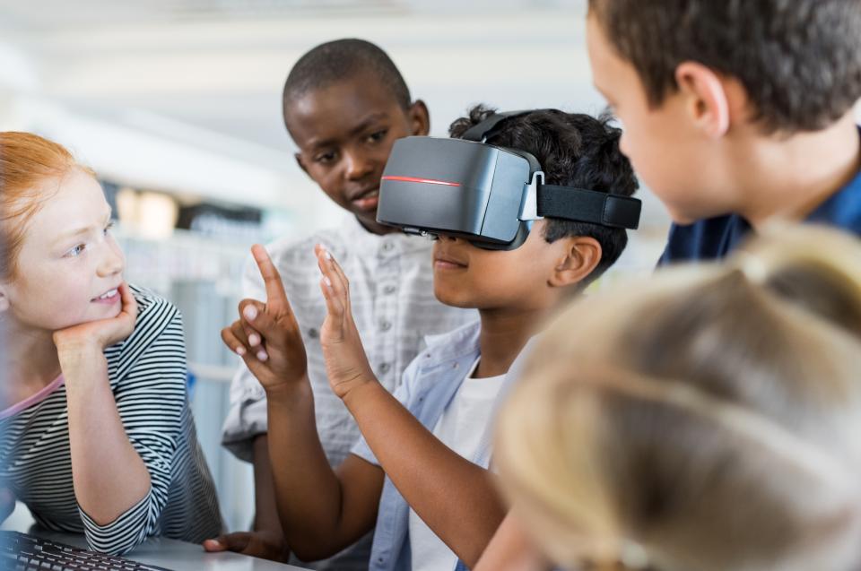 Grade-school children in a classroom play with a VR headset
