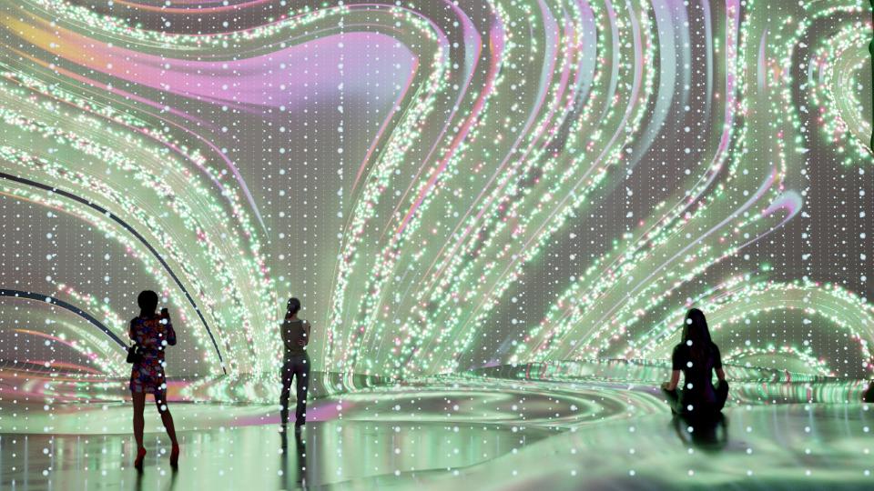 Wavy shaped art displayed on a large digital screen in a room