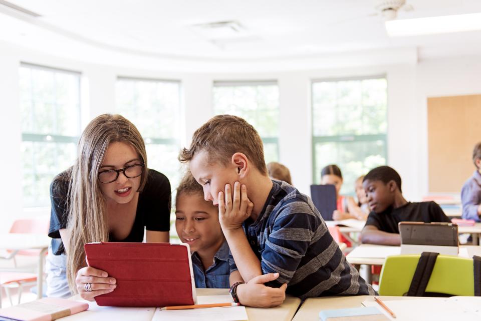 School children and a teacher in class using a digital tablet