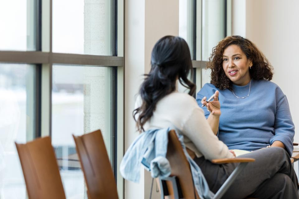 Two women seated, in deep conversation.