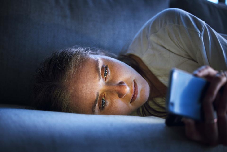 Woman lying on couch staring at her phone