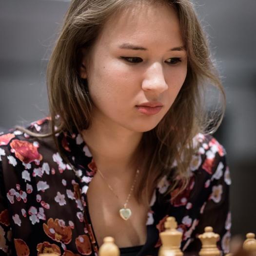 young woman looking down at chess board