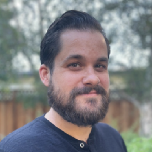 headshot half smiling with beard and navy blue shirt